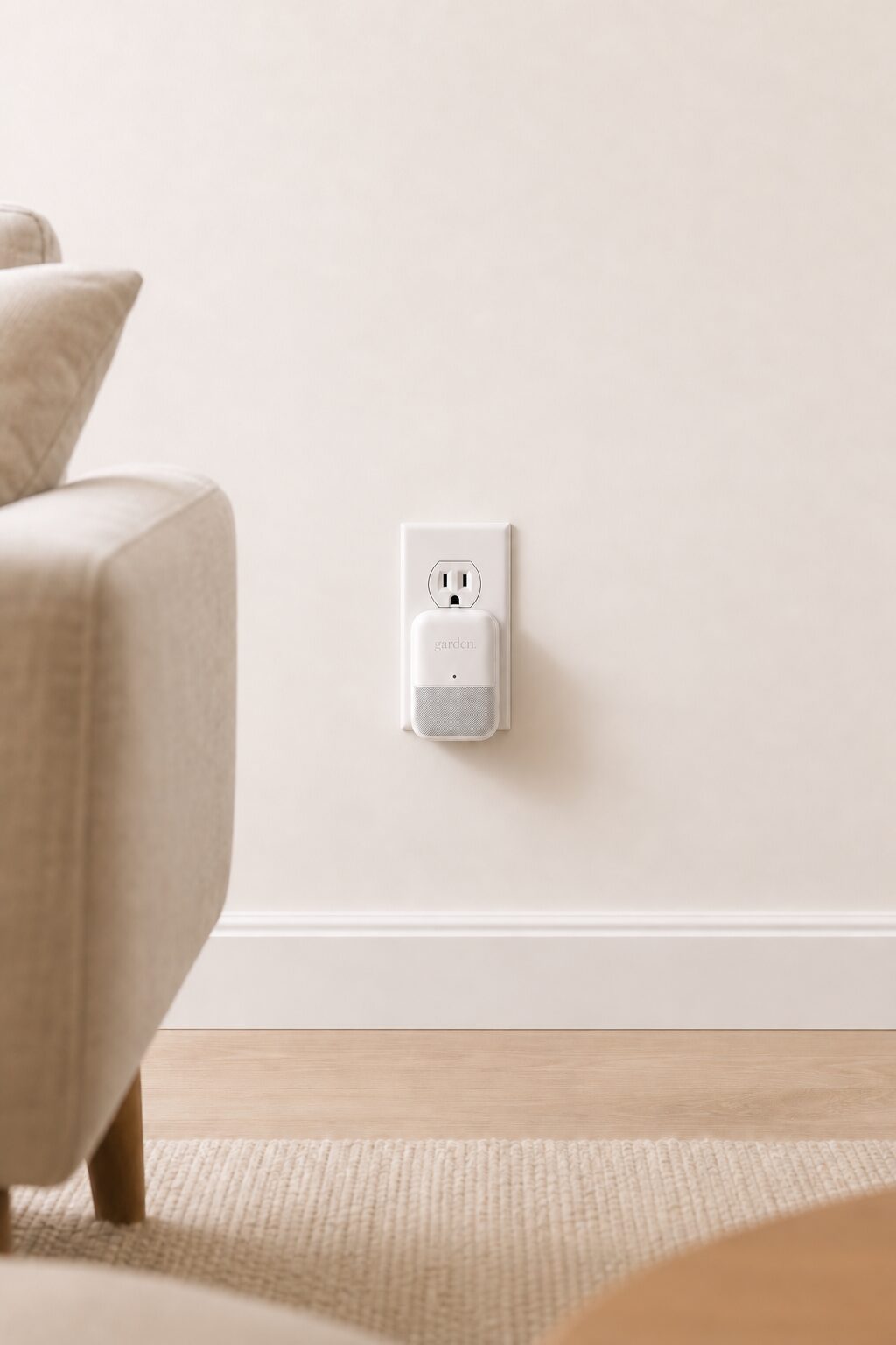 A Garden sensor plugged into a wall outlet beside a sofa.